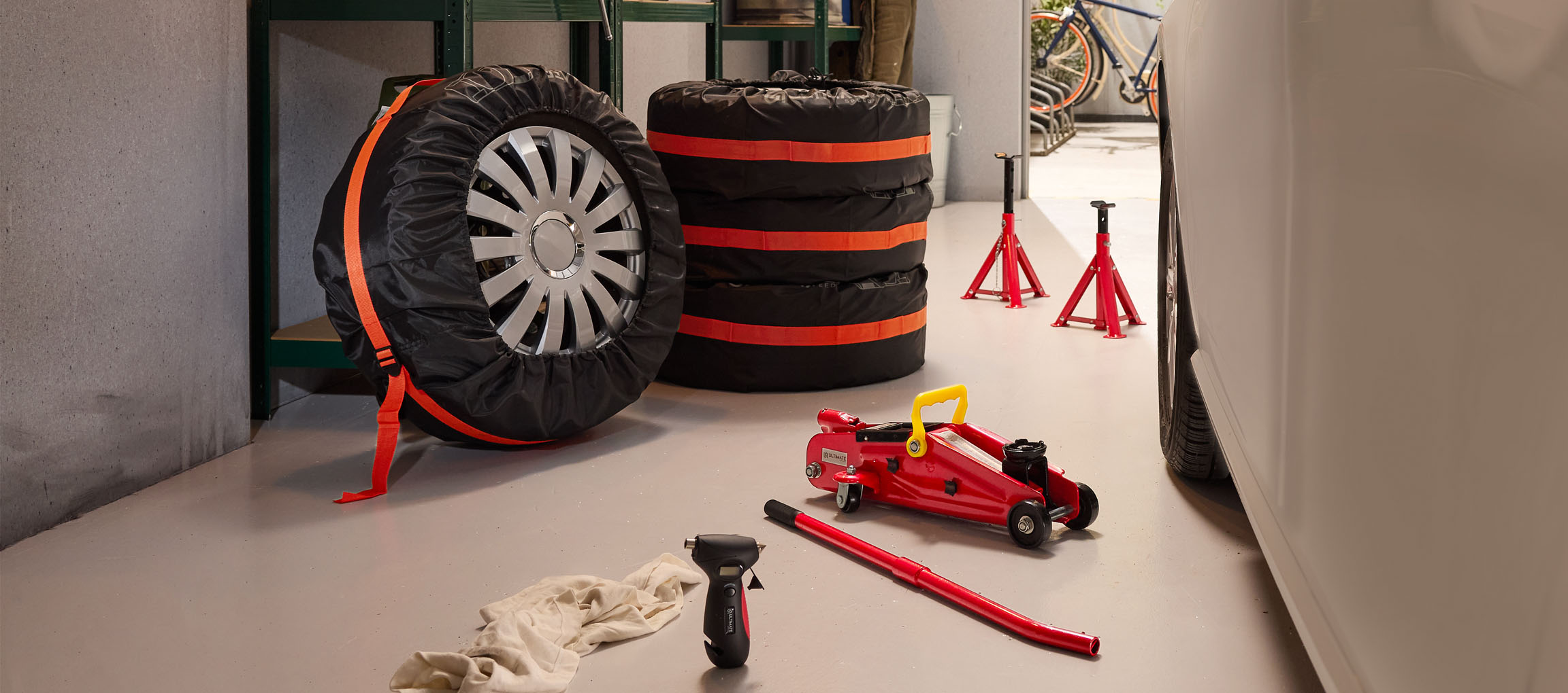 Автомобильные шины в чехлах, домкрат и подставки в гараже.