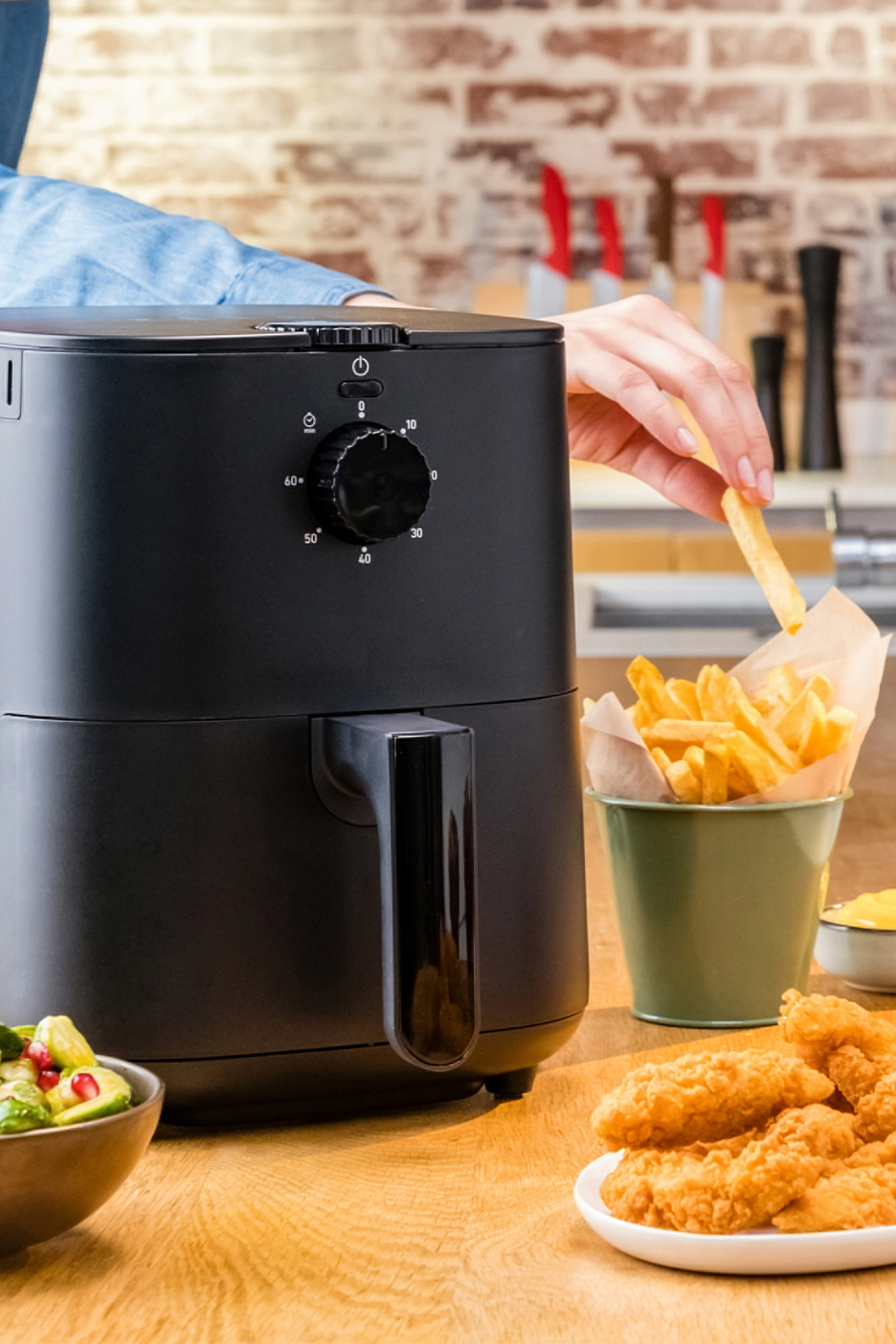 Must õhufritüür köögis koos friikartulite, kanatükkide ja salatiga.