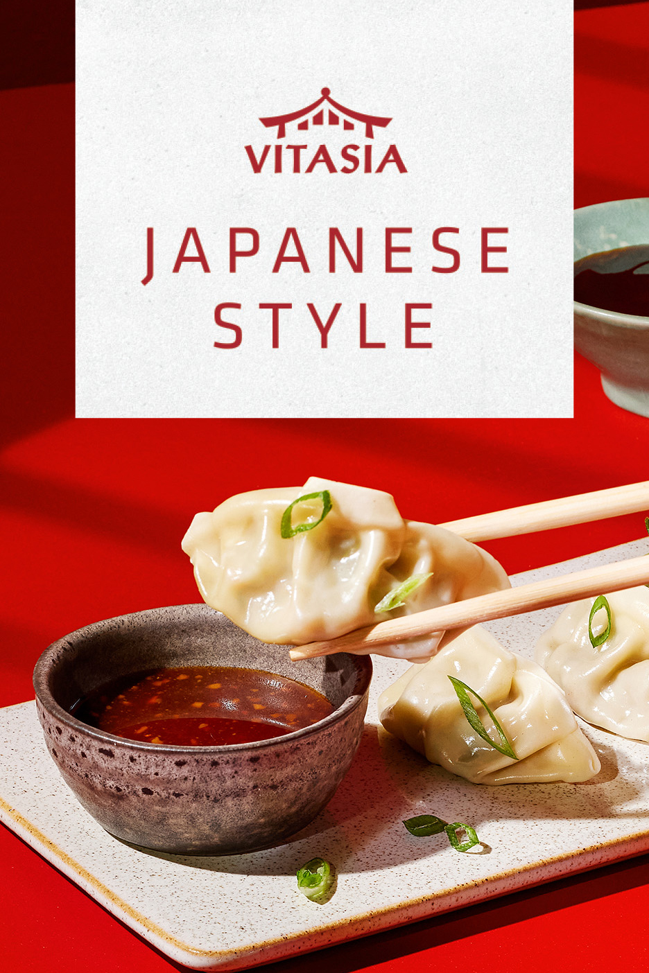 Jaapani stiilis pelmeenid sojakastmega, söögipulkadega tõstetud, punasel taustal.