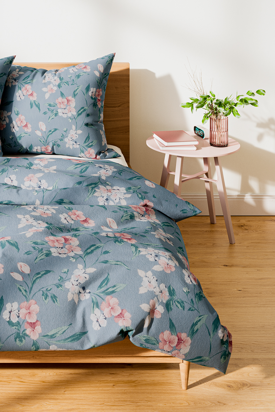 Sinine lillemustriga voodipesu magamistoas, roosa öökapi ja taimedega.