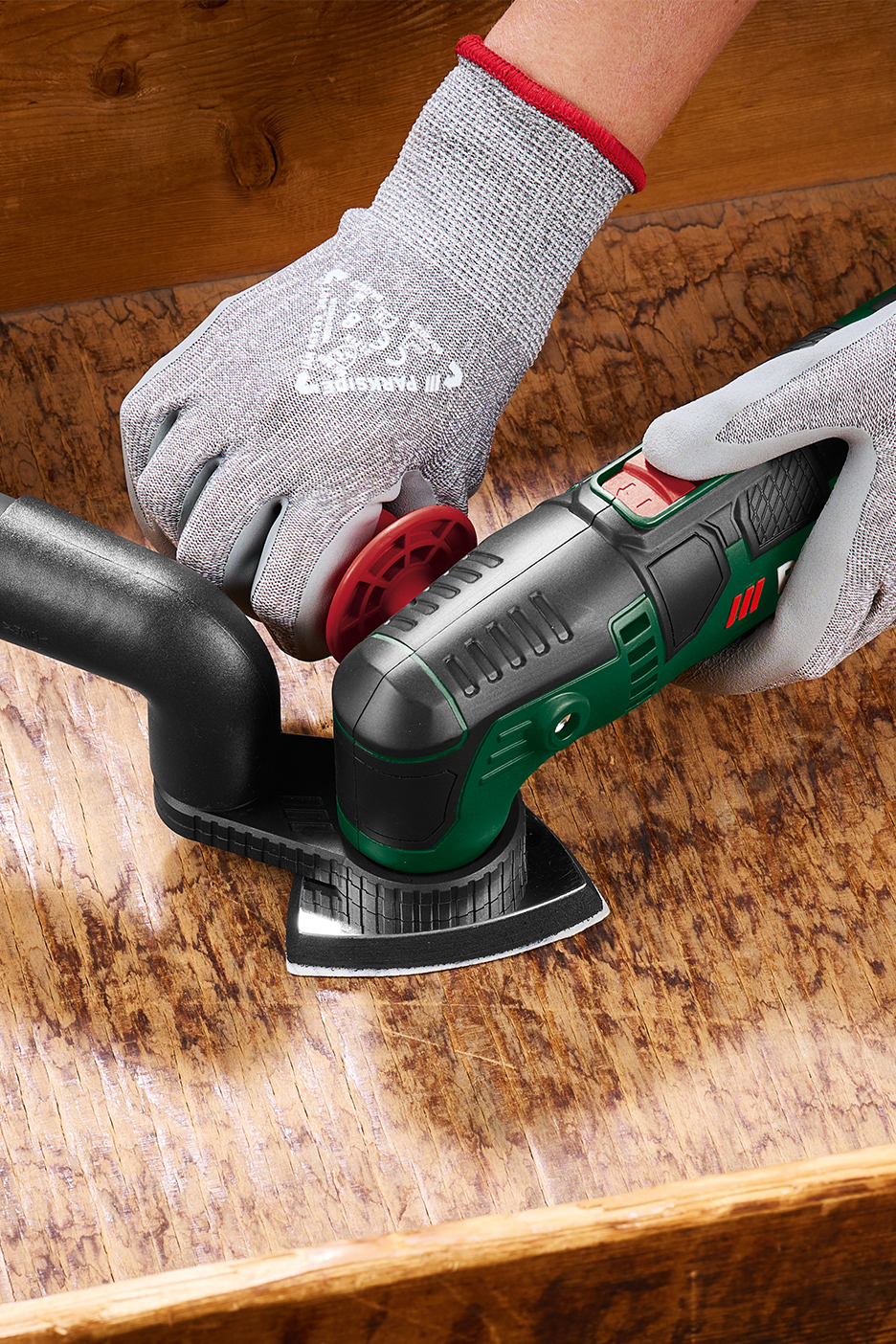 Kinnastes inimene lihvib puitpinda Parkside'i multifunktsionaalse tööriistaga.