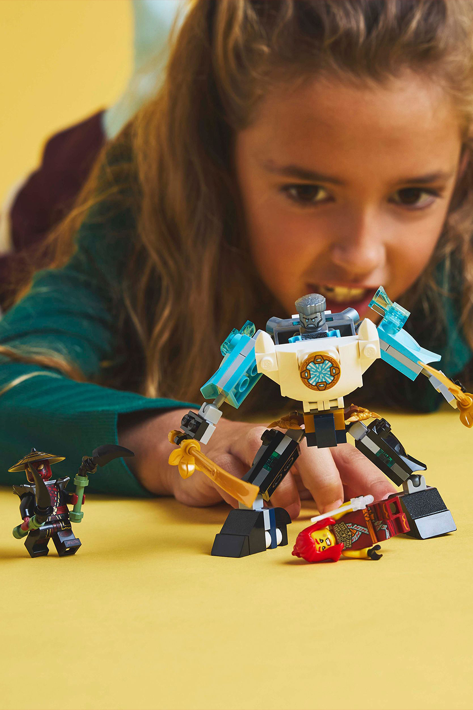 Tüdruk mängib kollasel taustal mänguasjade ja robotiga.