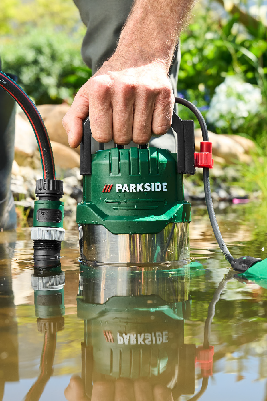 Mees laseb sukelpumba aiavoolikuga vette.