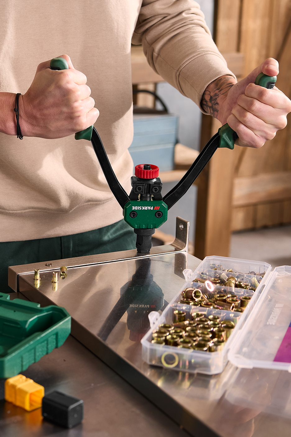 Inimene kasutab neetimispüstolit neetide paigaldamiseks metallpinnale.