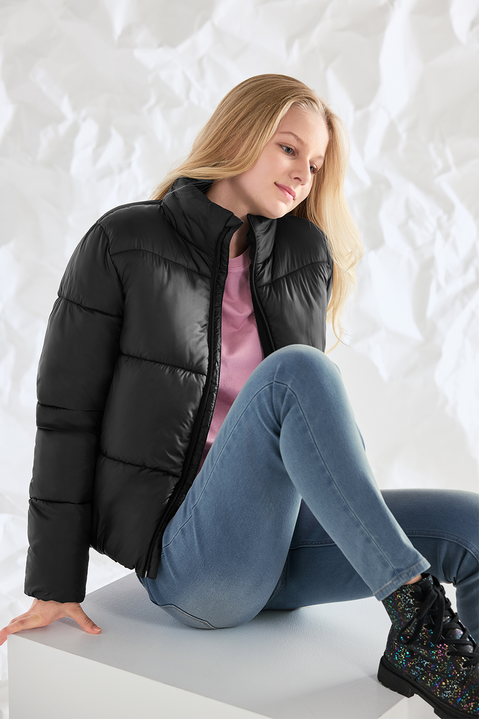 Tüdruk kannab musta puhvjopet, roosat T-särki, teksaseid ja musti saapaid.