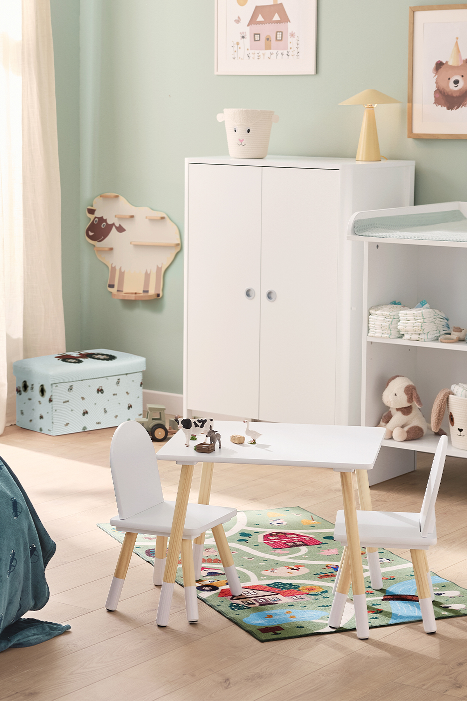Lastetuba valge kapi, mähkimislaua, laua ja toolidega ning taluteemalise vaibaga.