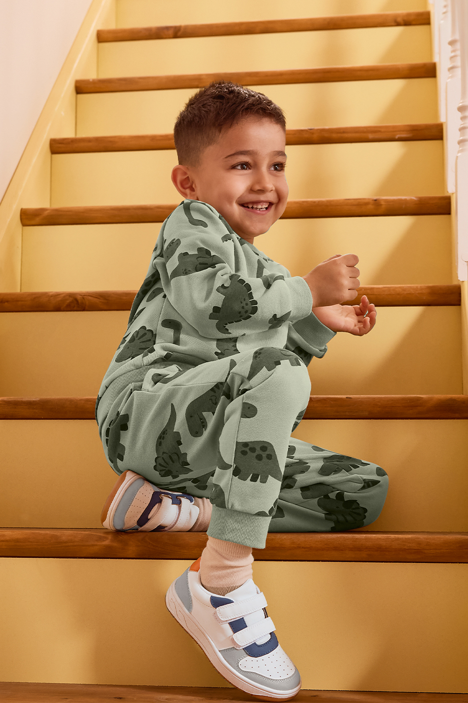 Poiss rohelises dinosaurustega dressikomplektis istub trepil.