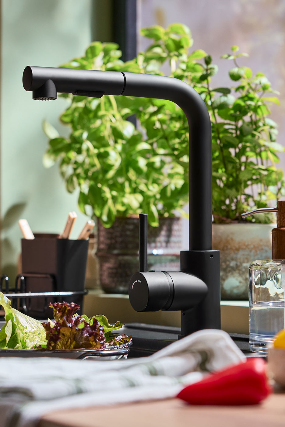 Must köögisegisti väljatõmmatava dušiga, värske salat ja paprika tööpinnale.