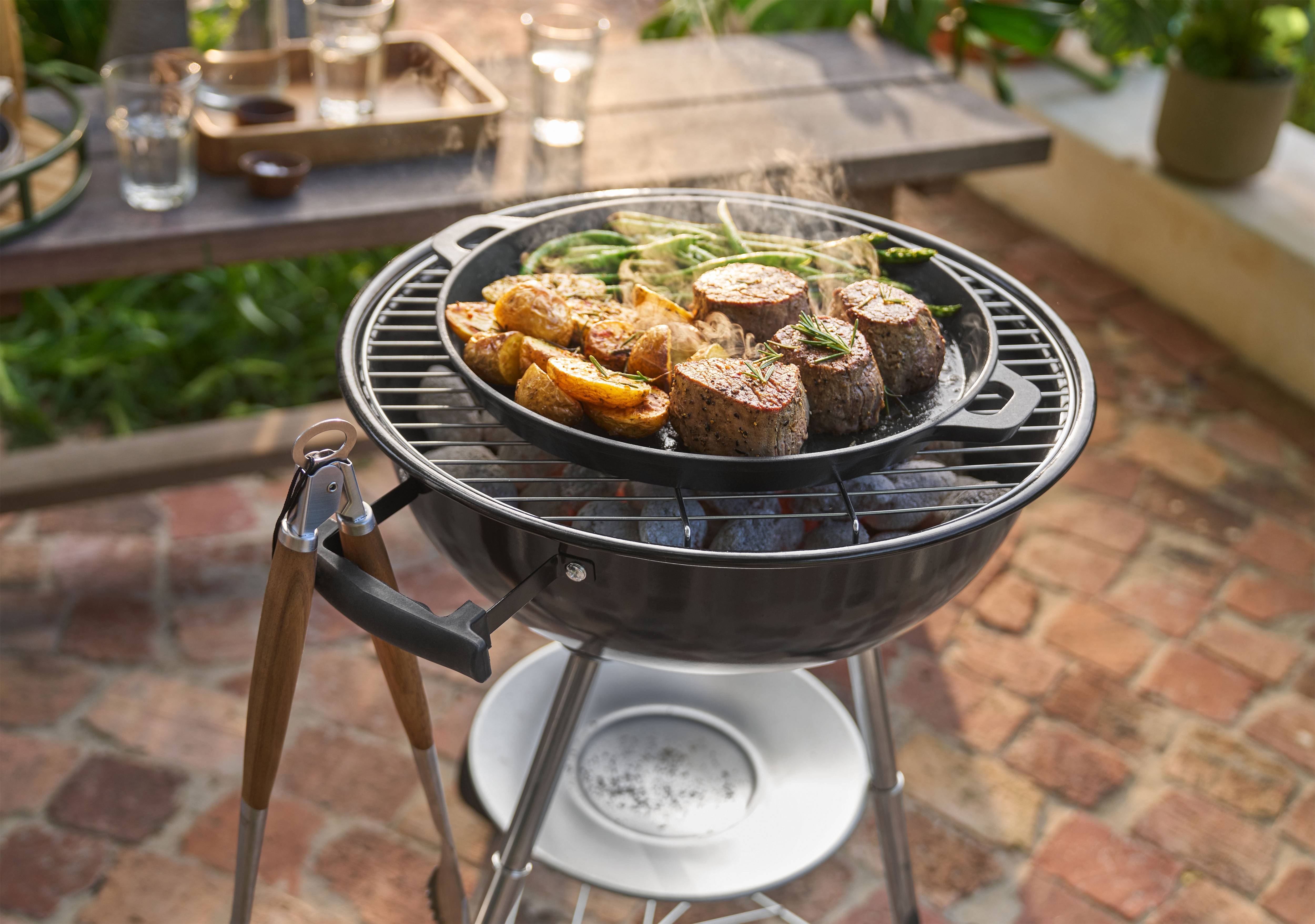 Grill liha, kartulite ja roheliste ubadega pannil õues küpsemas.