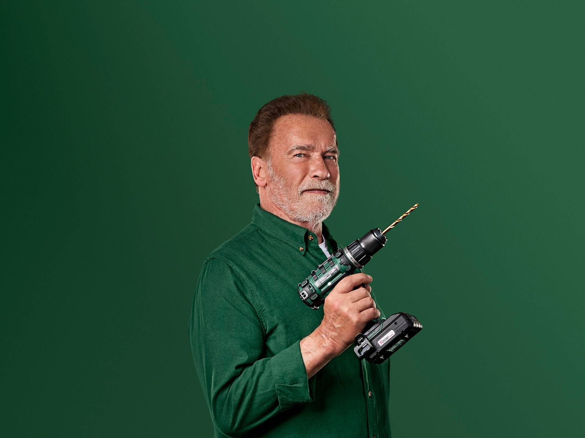 Arnold Schwarzenegger hoiab rohelist elektrilist puurit rohelisel taustal.