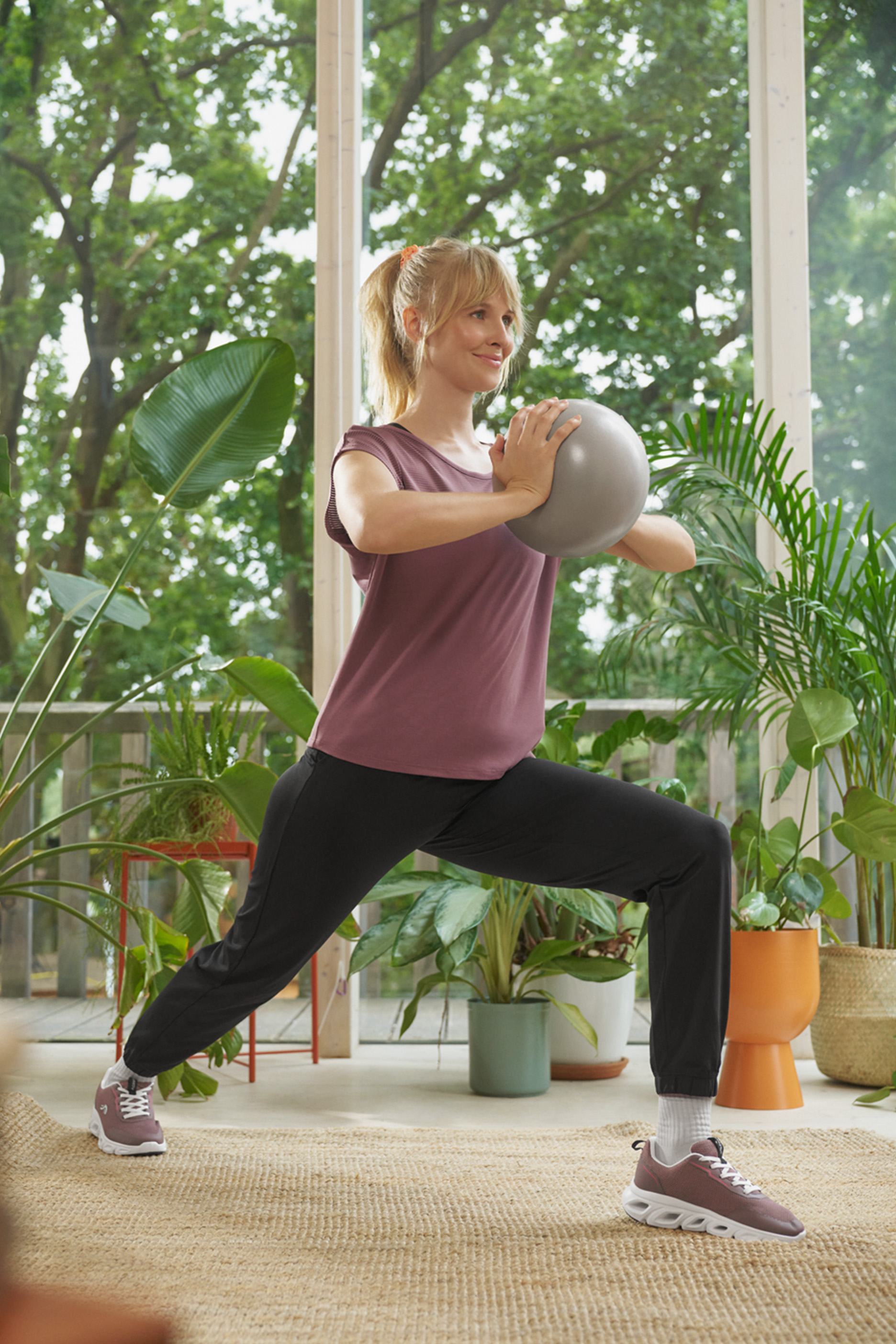 Naine spordiriietes teeb harjutusi pilatese palliga.