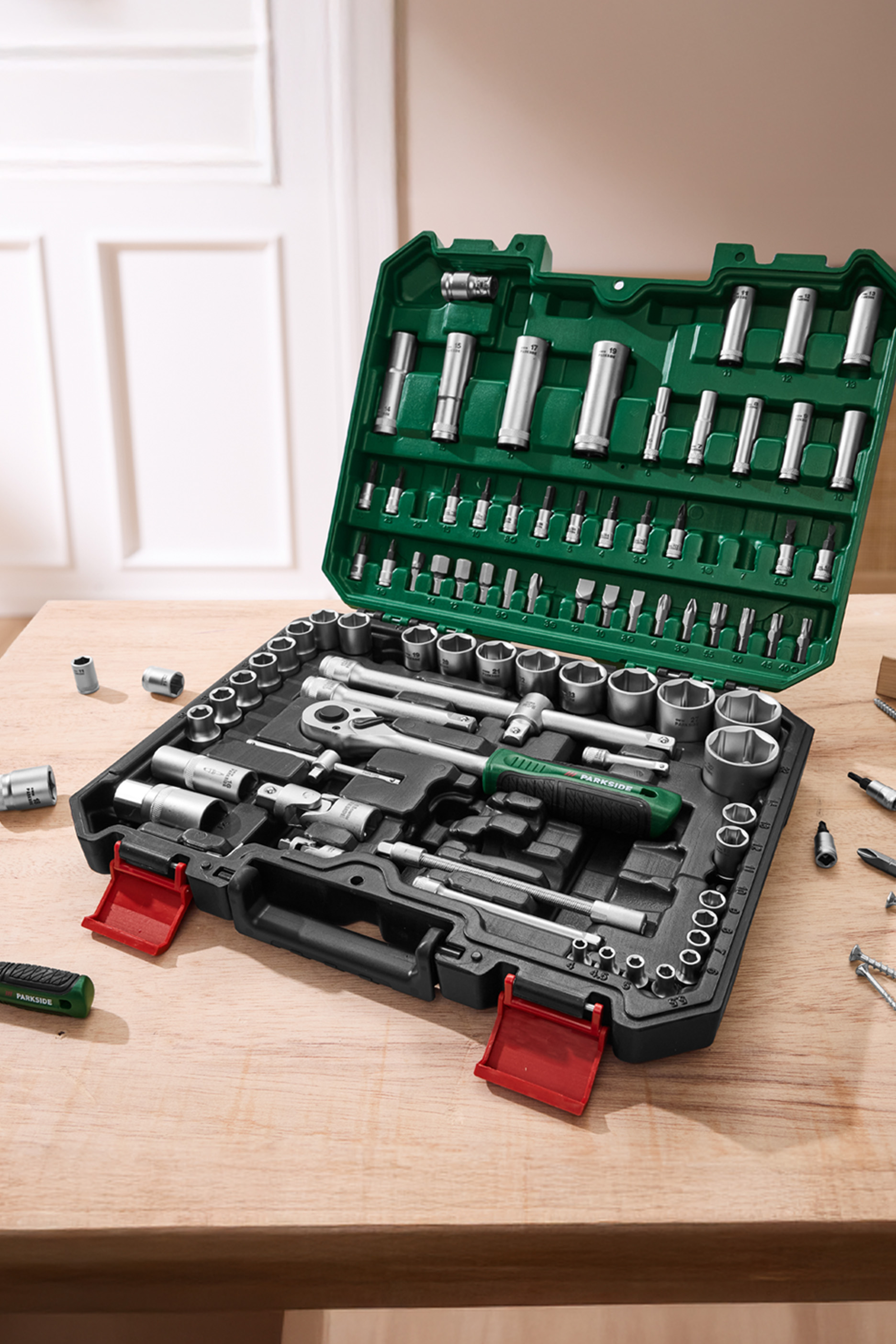 PARKSIDE tööriistakomplekt avatud rohelises karbis, näidates mutrivõtmeid ja otsikuid puidust laual.