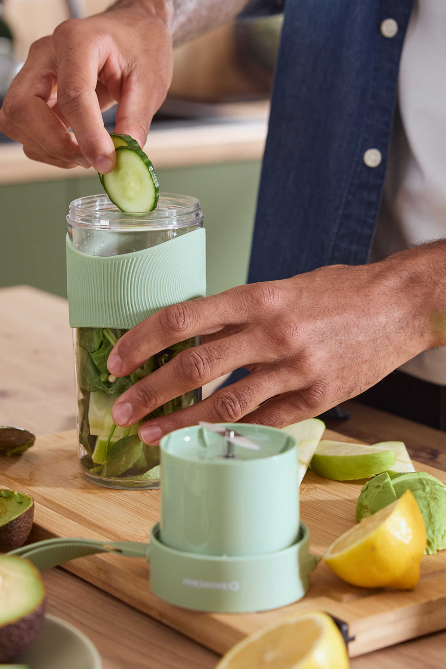 Inimene lisab kurgi kaasaskantavasse blenderisse koos rohelistega.