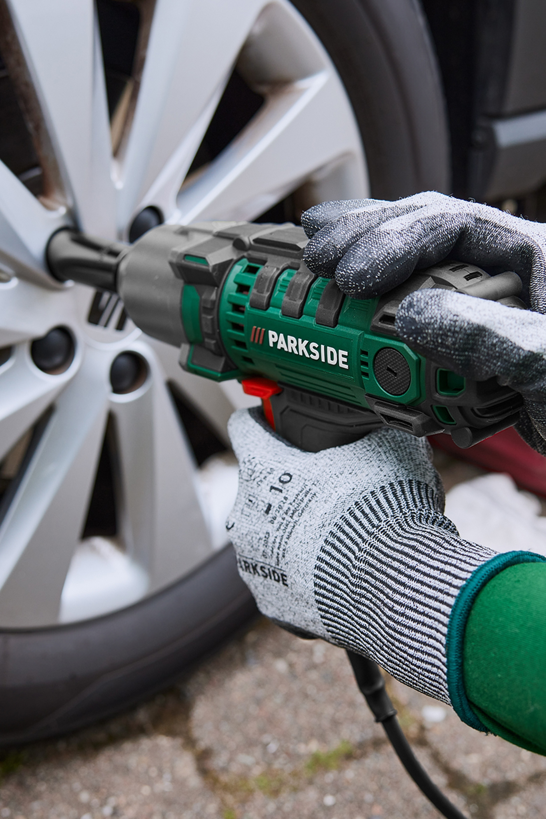 Inimene kasutab mutrikeerajat auto ratta mutrite pingutamiseks või lahti keeramiseks.