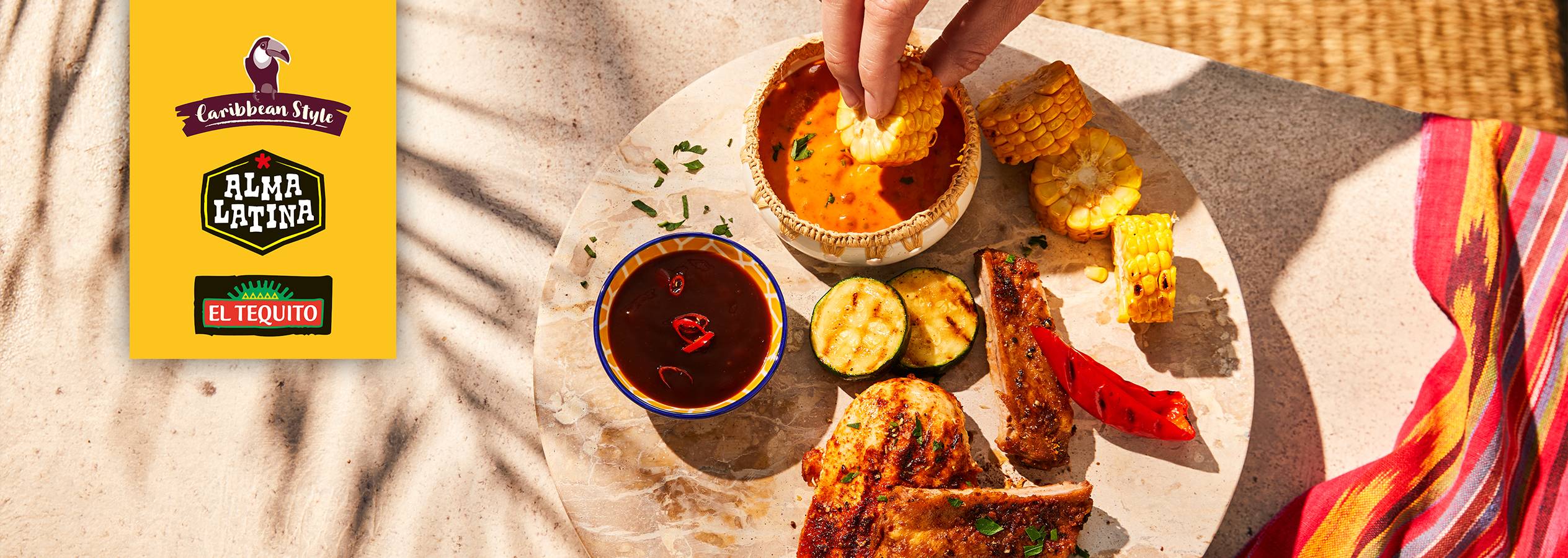 Еда в карибском стиле с кукурузой, мясом, соусами и логотипами брендов.