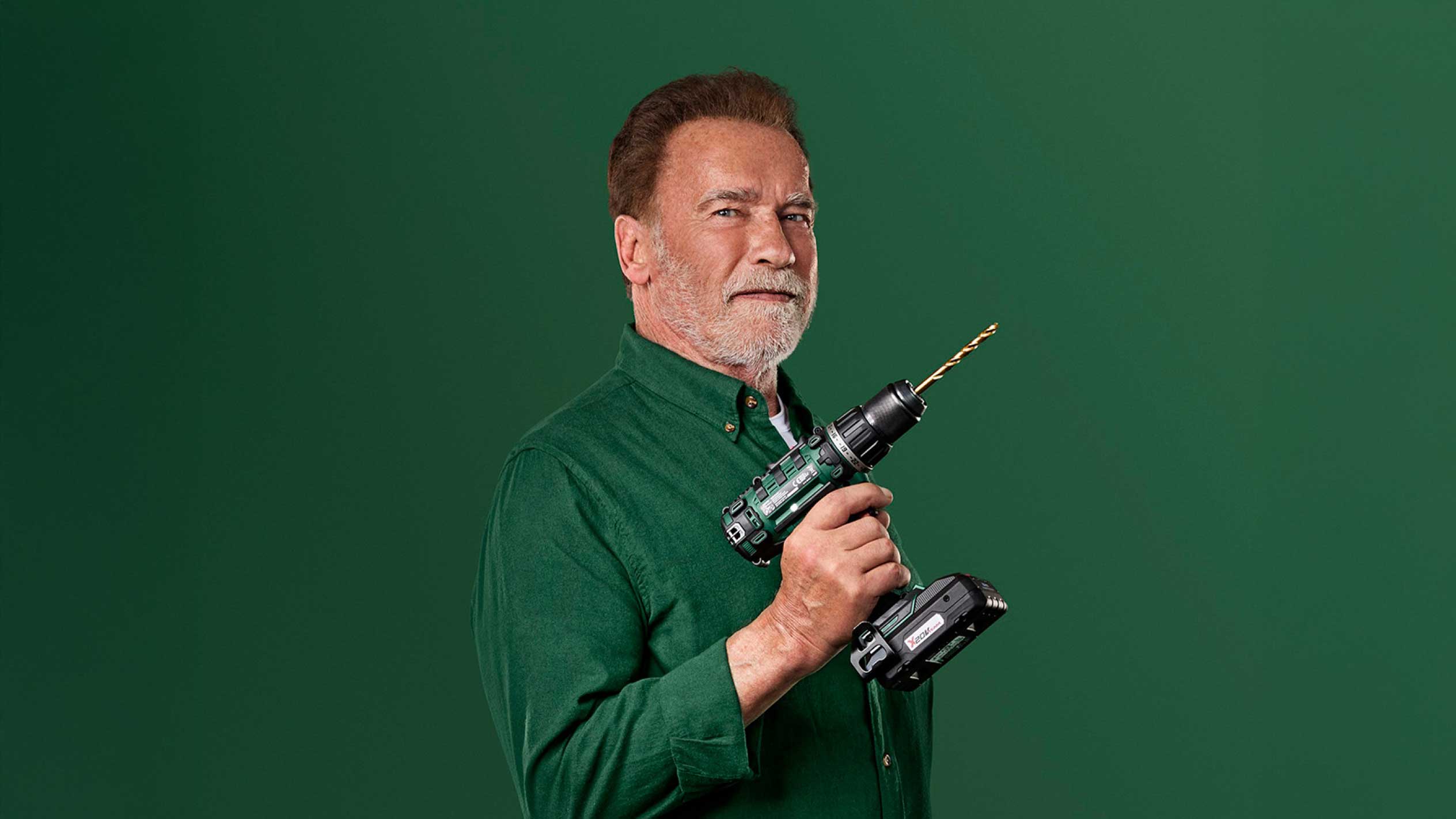 Arnold Schwarzenegger hoiab rohelist akutrelli kuldse puuriteraga.