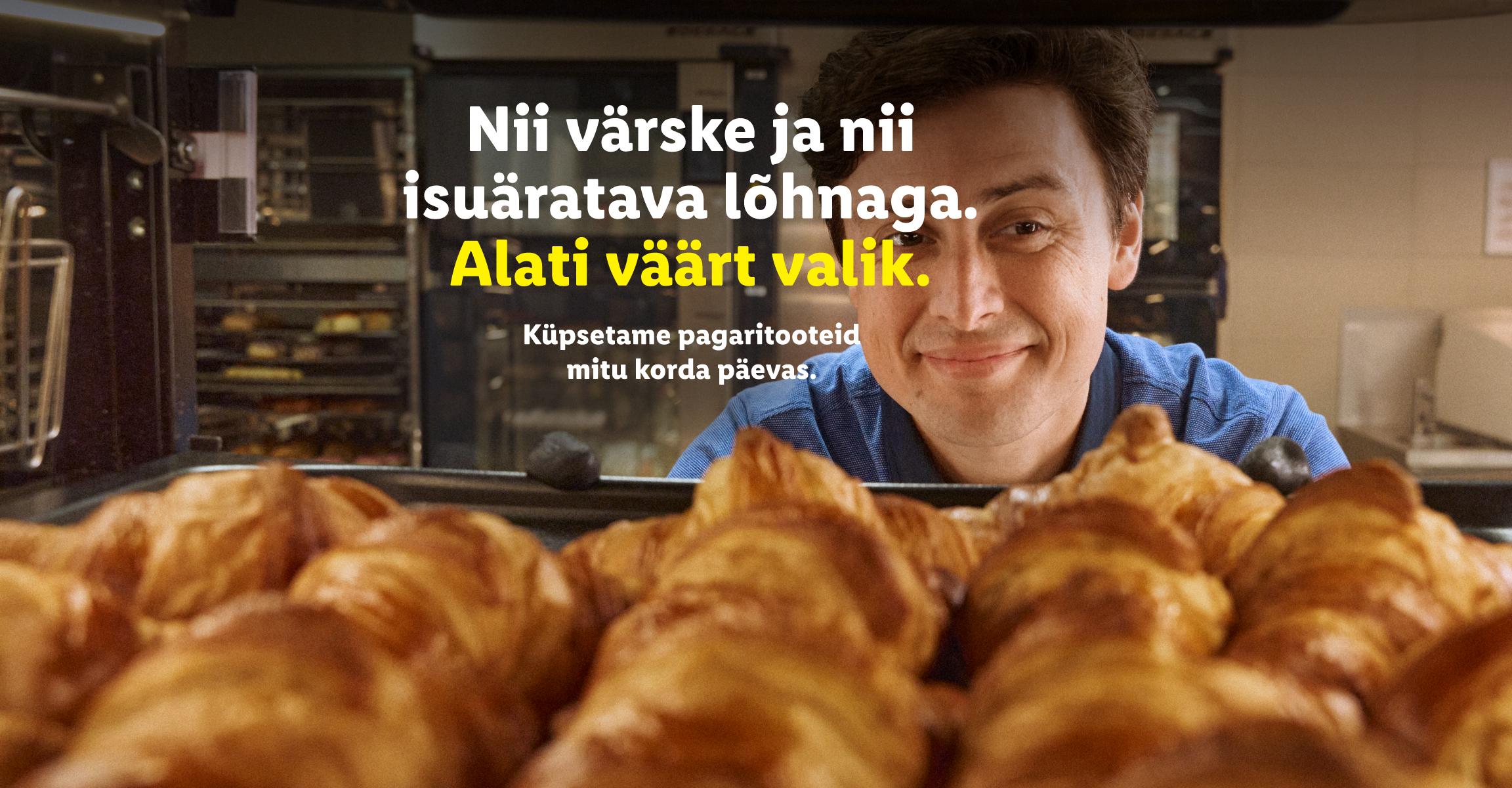 Meessoost pagar naeratab kaamera poole, taustal ahjud ja ees värsked sarvesaiad. Tekst: 'Nii värske ja nii isuäratava lõhnaga. Alati väärt valik. Küpsetame pagaritooteid mitu korda päevas.'