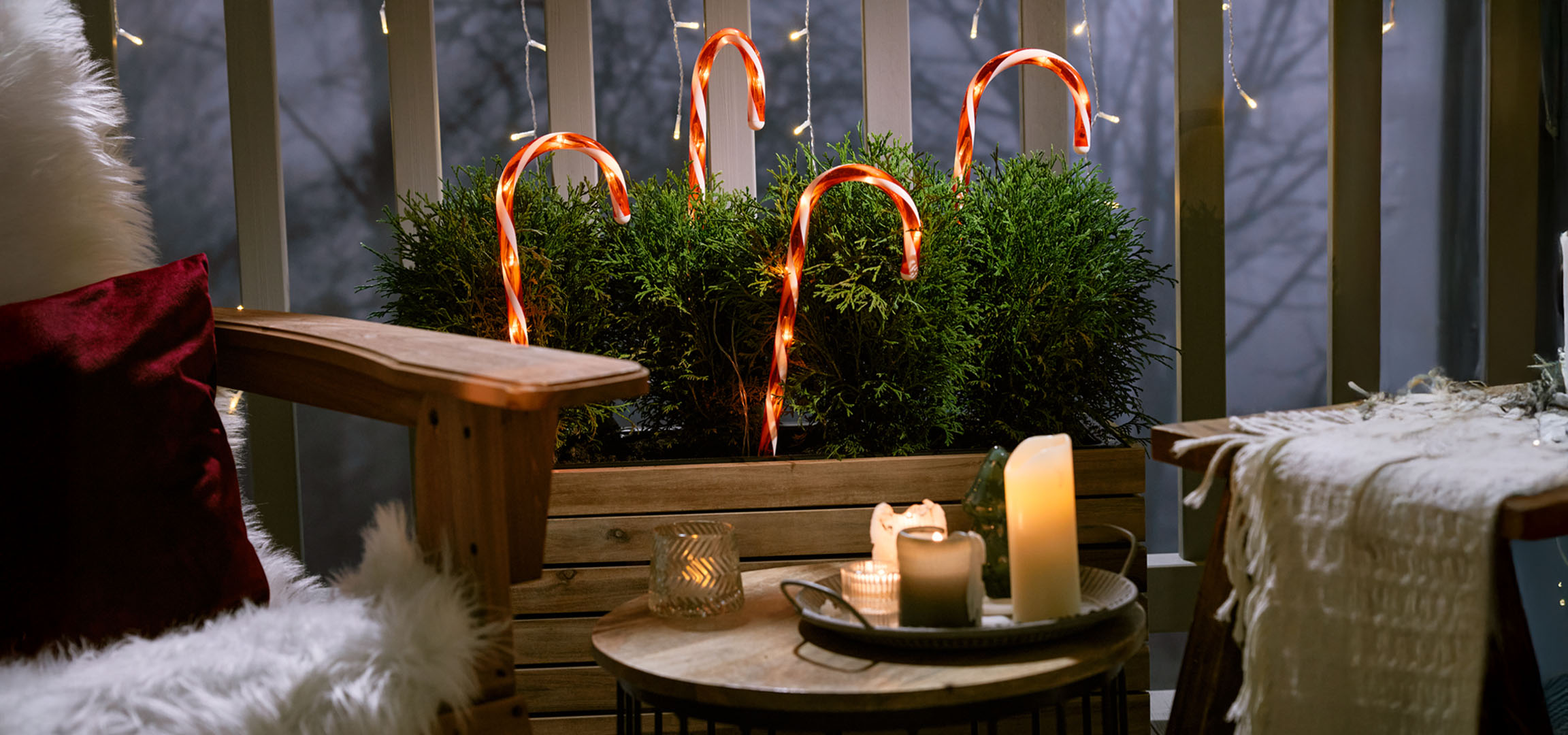 Jõuludeks kaunistatud rõdu tooli, küünalde ja kommikeppidega.