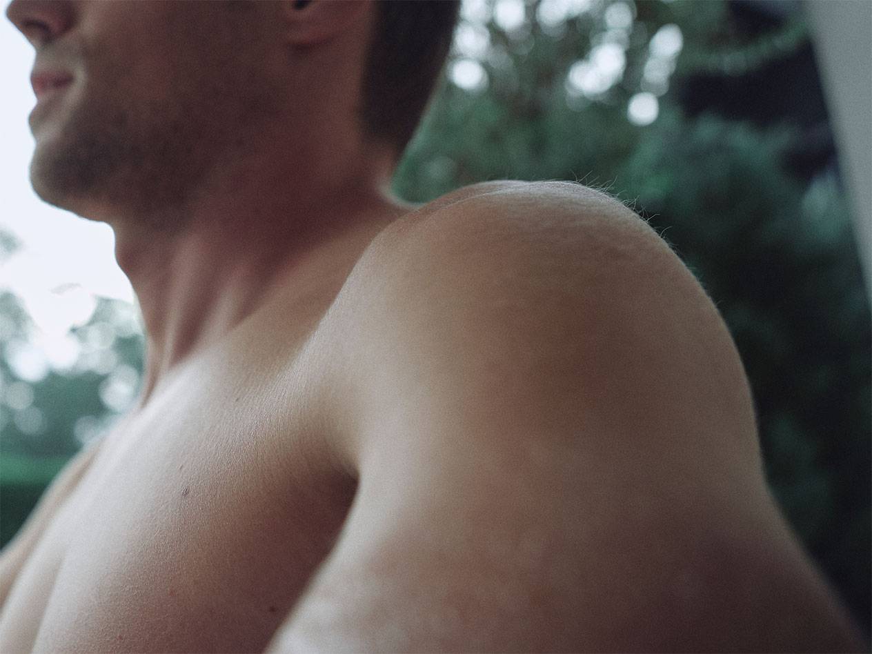 Lähivõte mehe õlast ja kaelast, udune roheline taust.