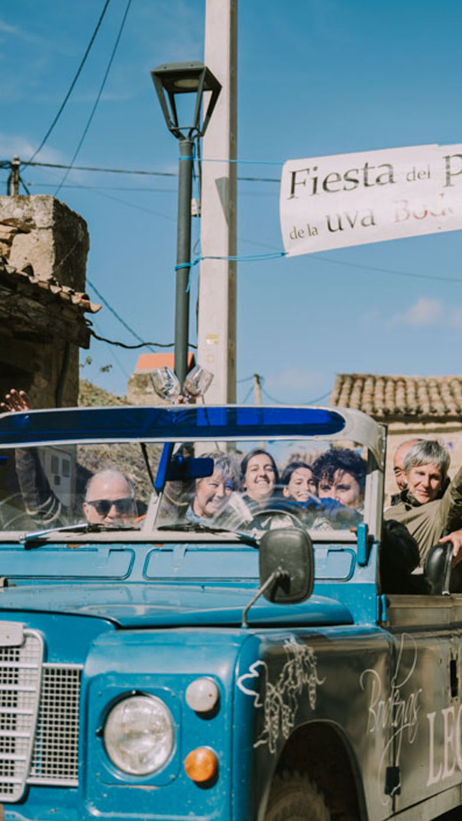 Inimesed sinises autos bänneri all, millel on kiri 'Fiesta del P de la uva Bod'.