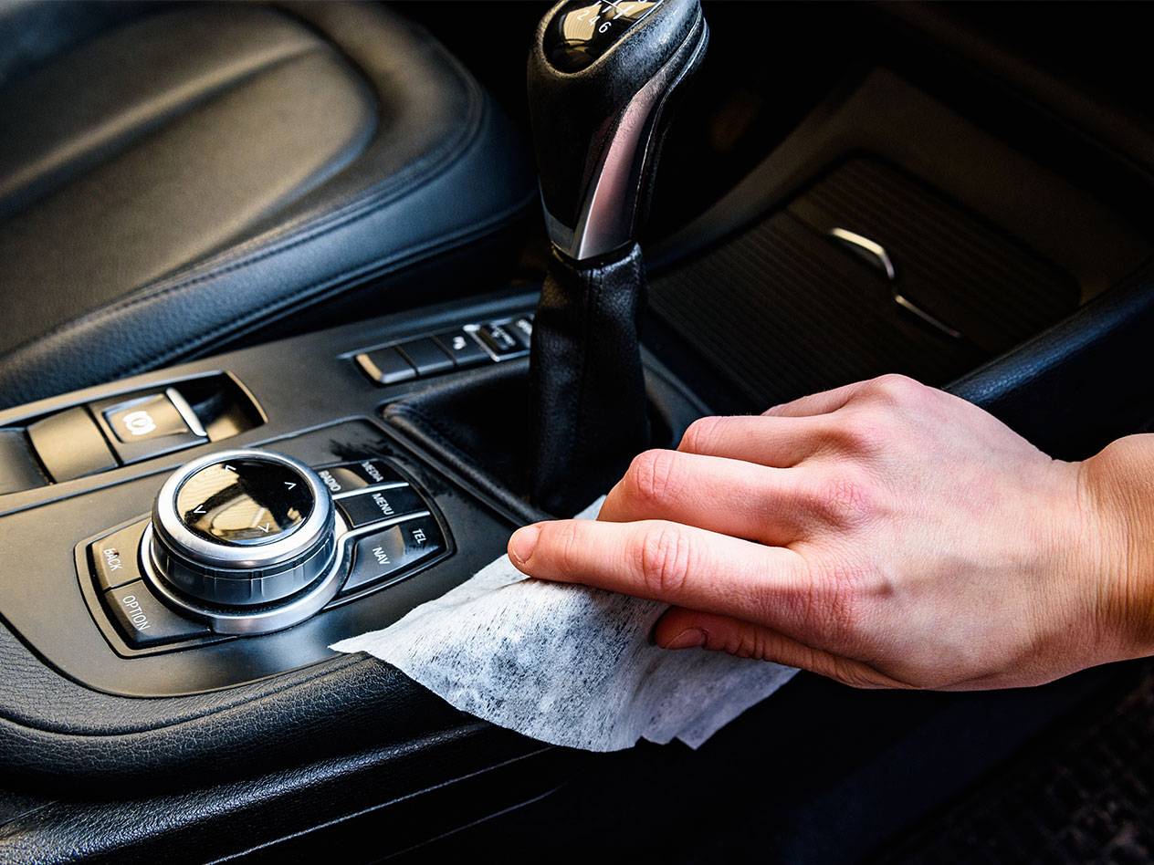 Käsi puhastab auto sisemust niiske lapiga.
