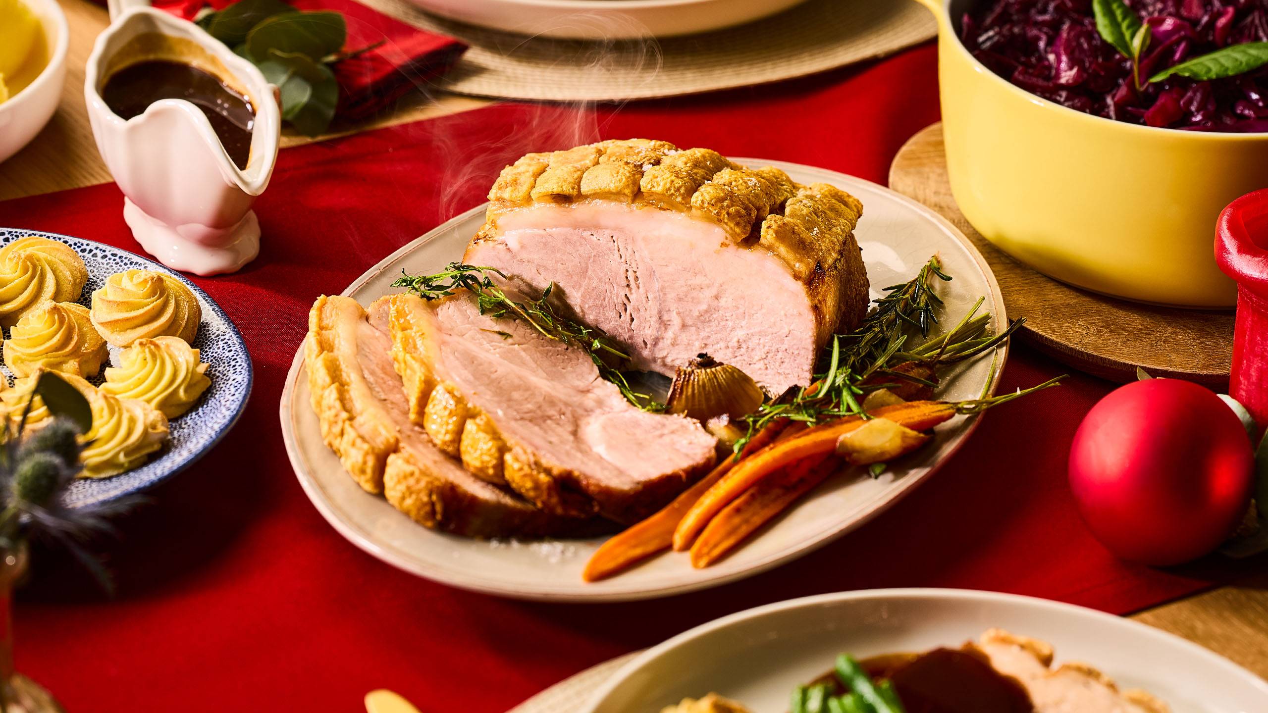 Рождественский стол со свиным жарким, картофельным пюре, красной капустой и соусом.