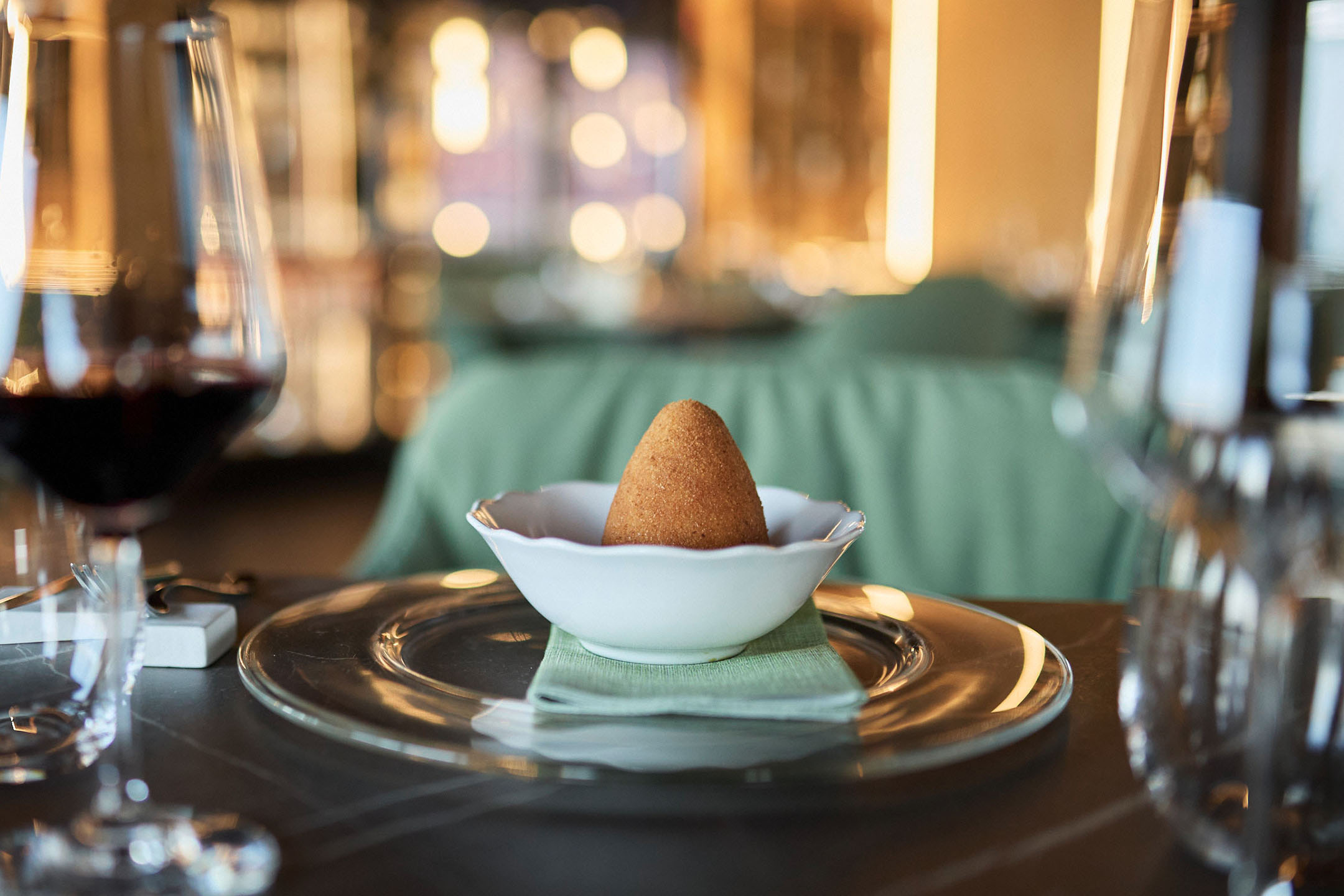 Kuldne arancini valges kausis elegantsel restoranilaual.