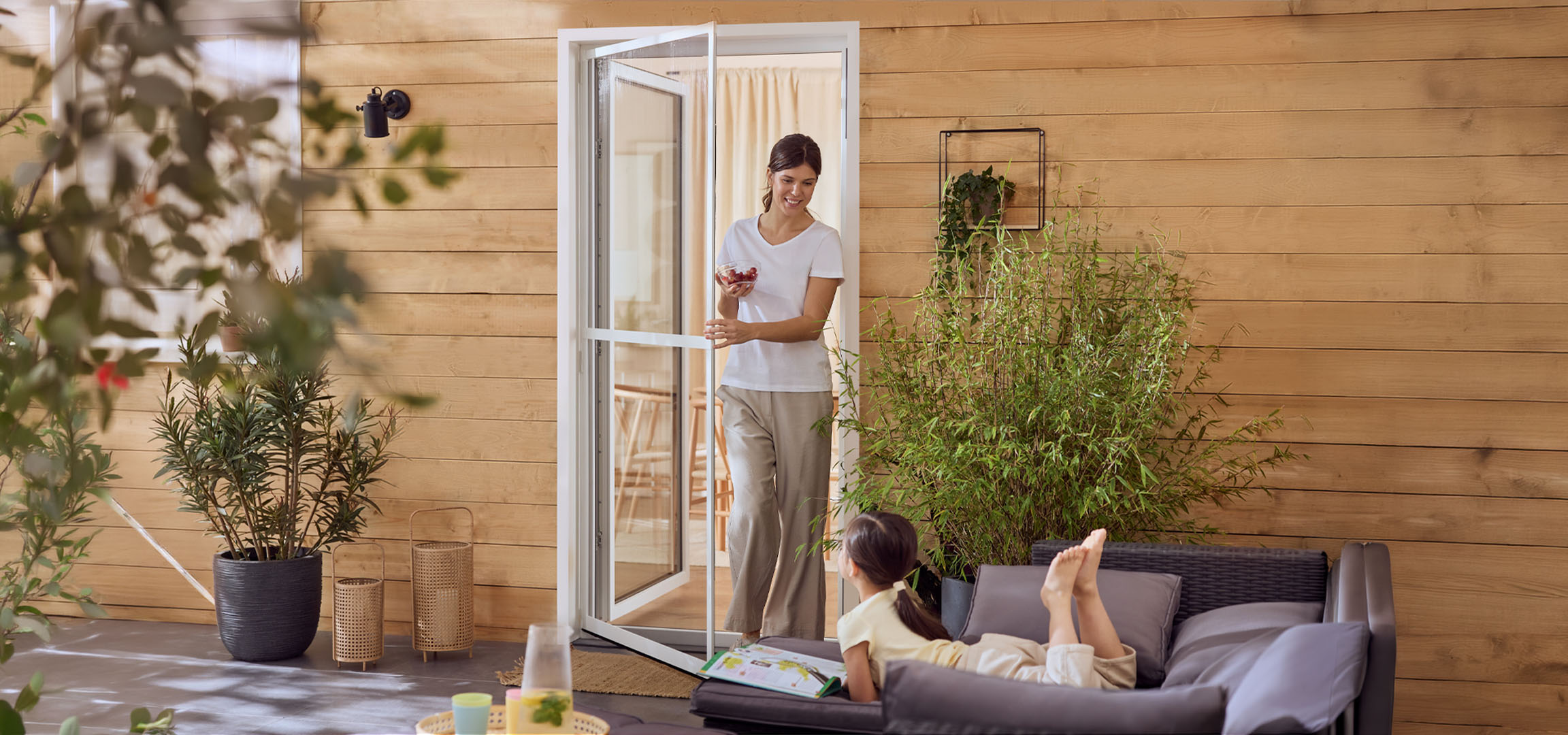 Naine ja tüdruk naudivad terrassi välimööbli ja taimedega.