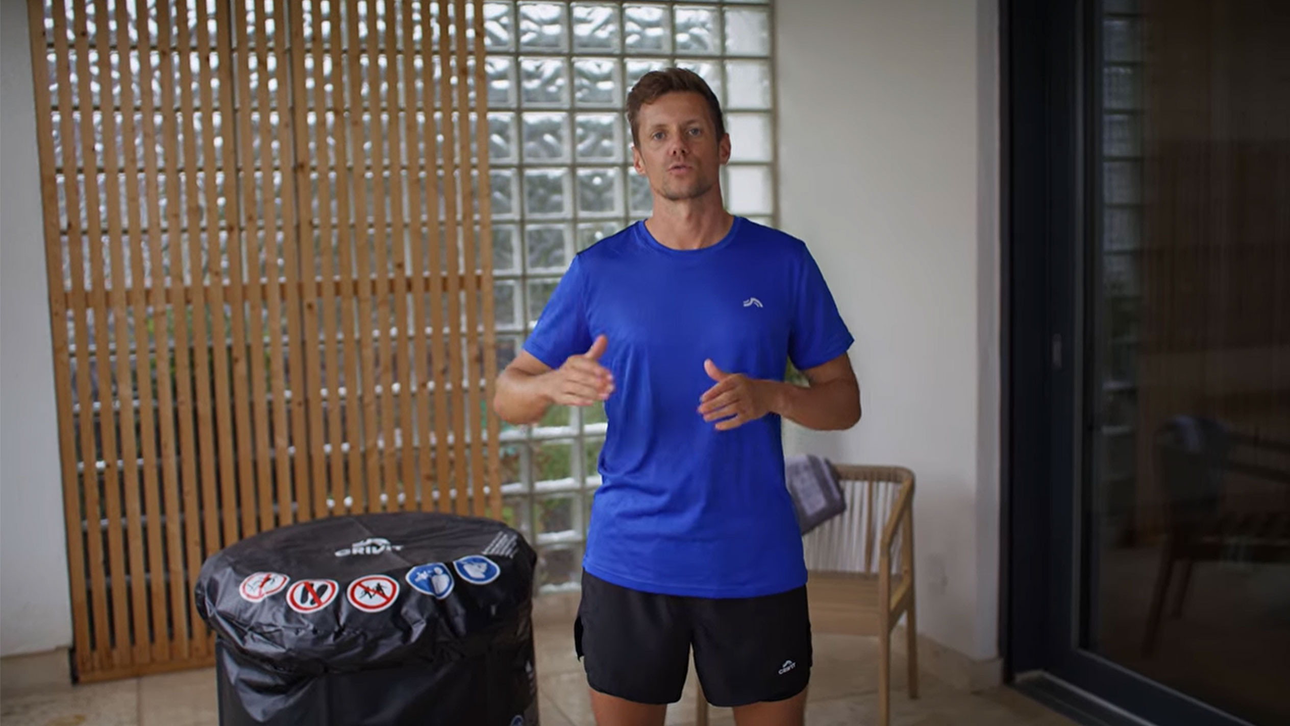 Mees sinises T-särgis ja mustades lühikestes pükstes, musta mullivanni katte kõrval.