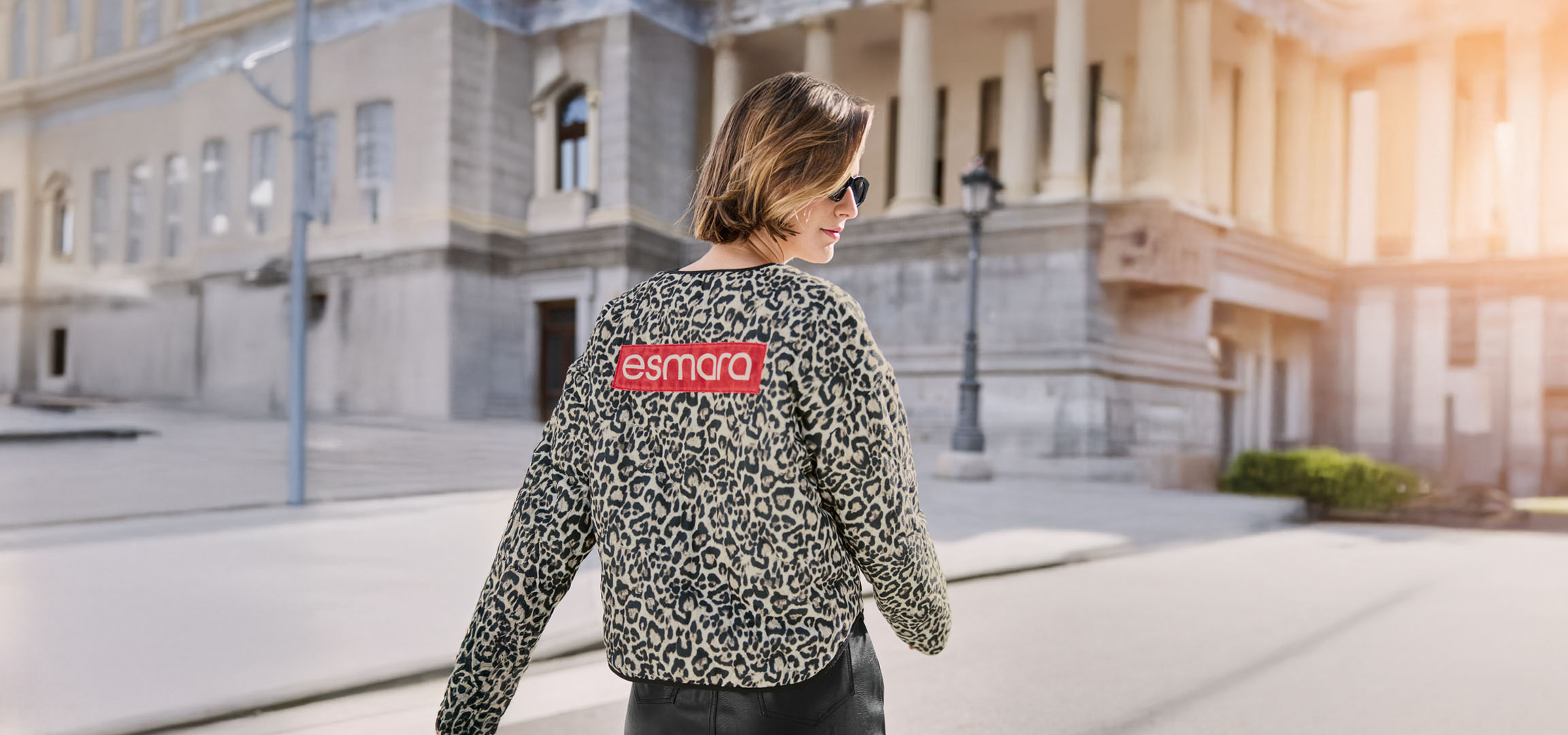 Naine Esmara leopardimustrilises jakis, päikeseprillides, linnatänaval.