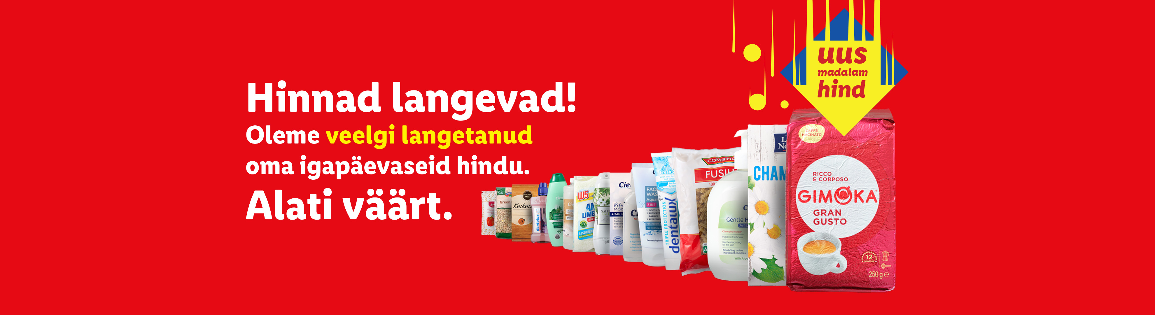 Punane bänner tekstiga 'Hinnad langevad! Oleme veelgi langetanud oma igapäevaseid hindu. Alati väärt.' ja toodetega nagu kohv, šampoon ja puhastusvahendid.
