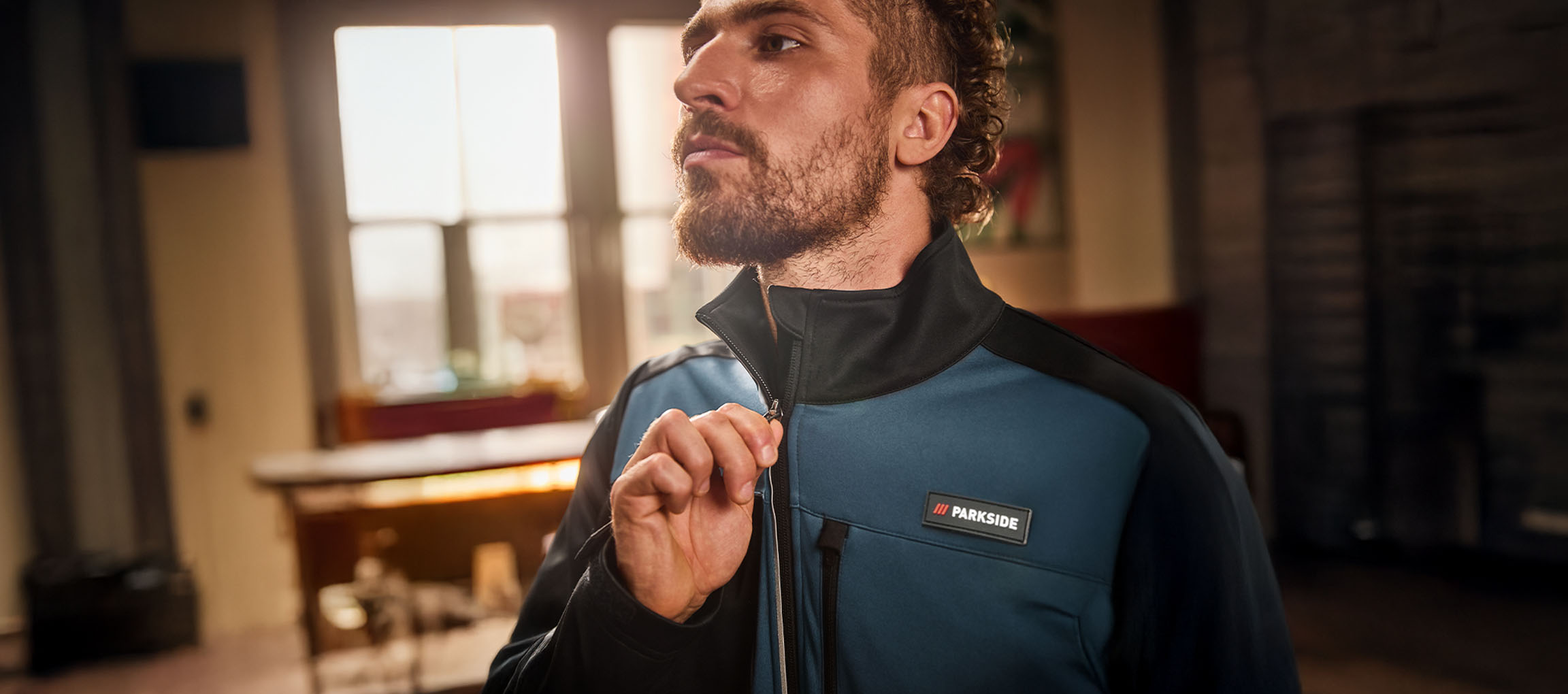 Mees sinises ja mustas Parkside tööjakis, tõmbab lukku kinni