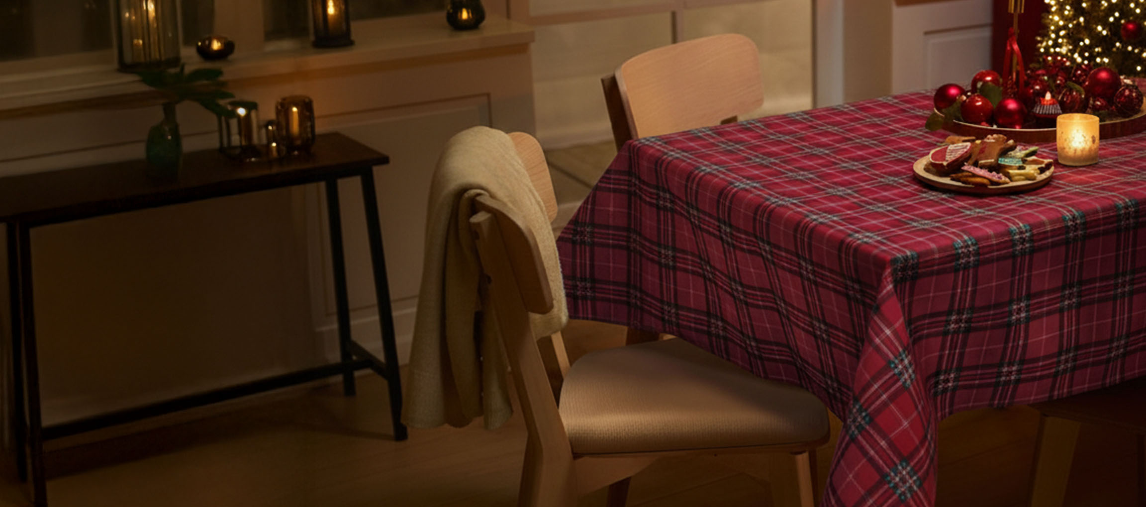 Jõululaud punase ruudulise laudlina, toolide ja jõuluküpsistega.