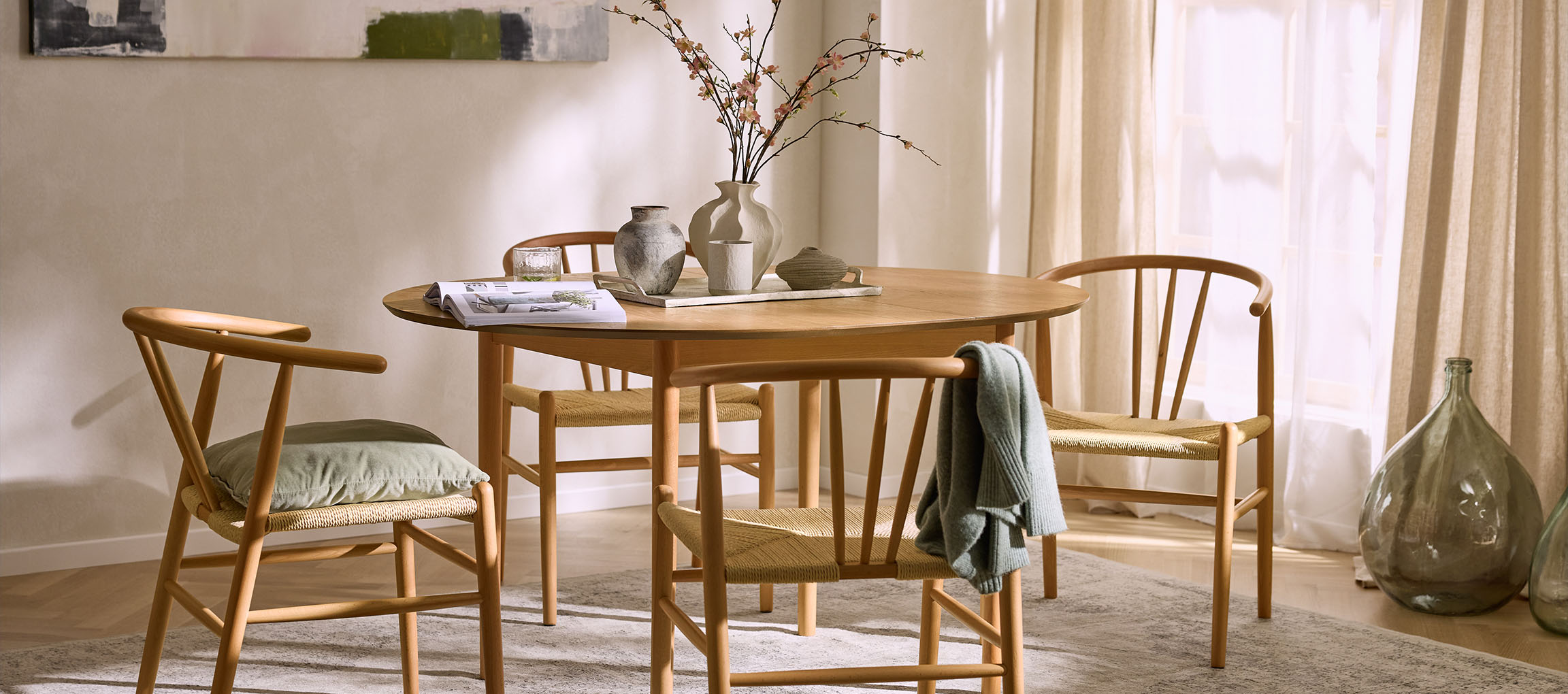 Söögitoa sisustus ümmarguse puidust laua, nööriga istmetega puidust toolide ja dekoratiivsete vaasidega.