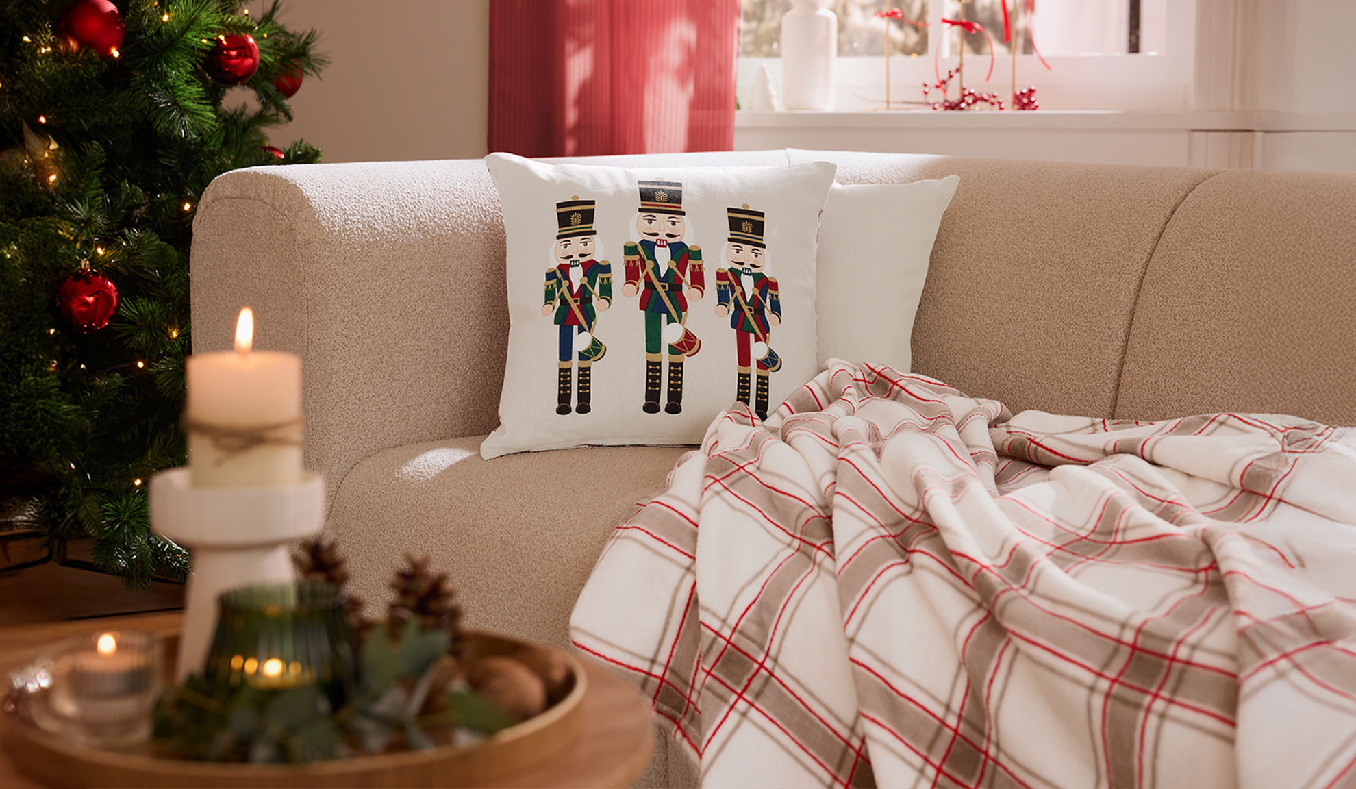 Jõulune elutuba diivani, pähklipureja patjade, ruudulise pleedi ja küünaldega.
