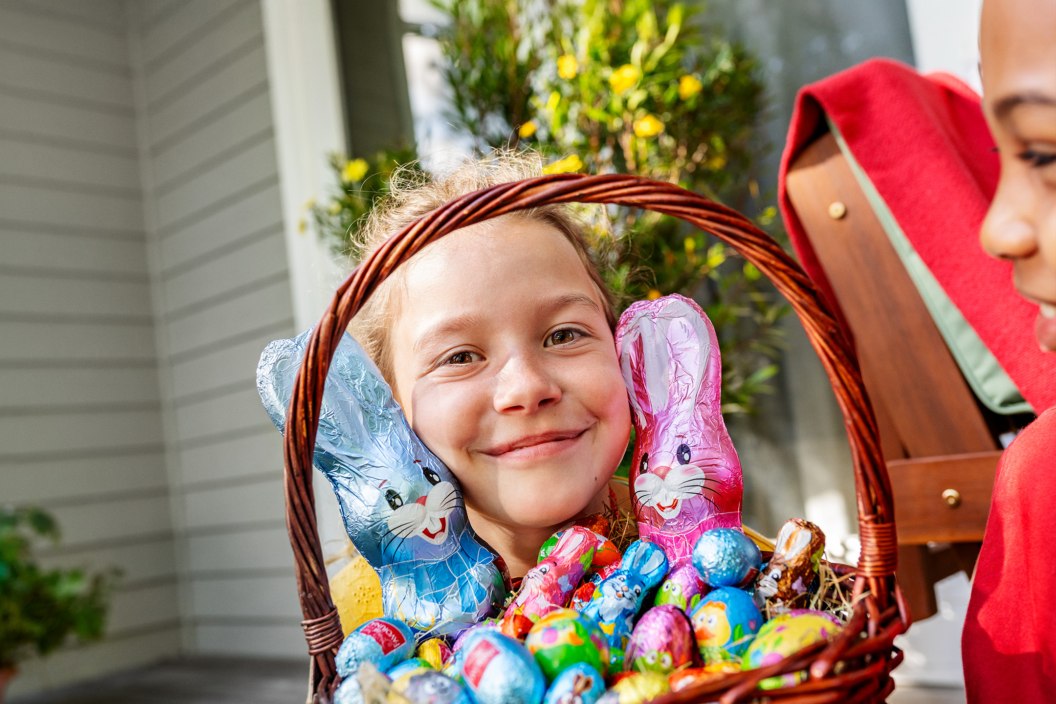 Девочка с корзиной, полной шоколадных пасхальных яиц и кроликов