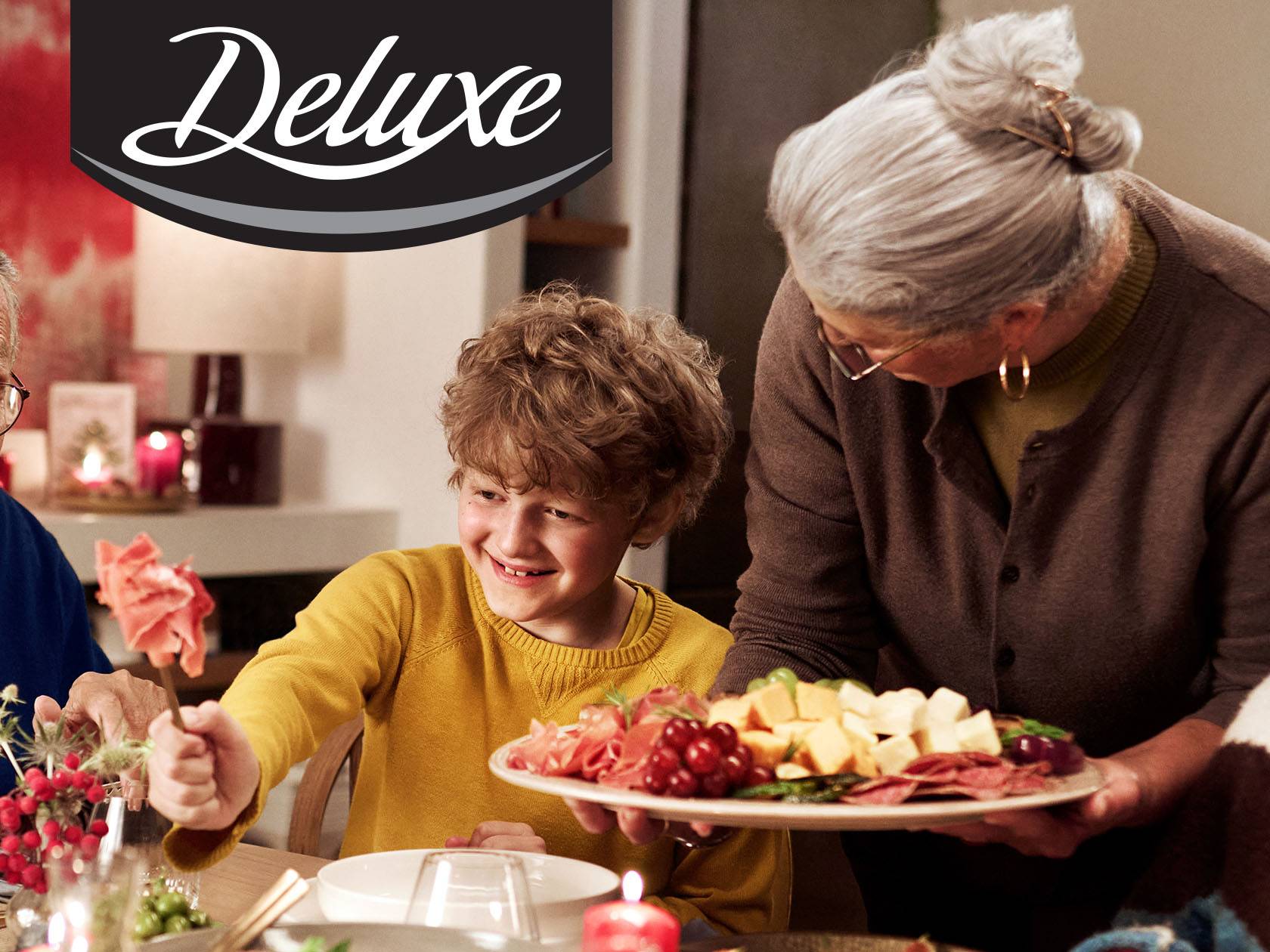 Deluxe suupistevaagen juustu, singi ja viinamarjadega, mida serveerib vanem naine lapsele.