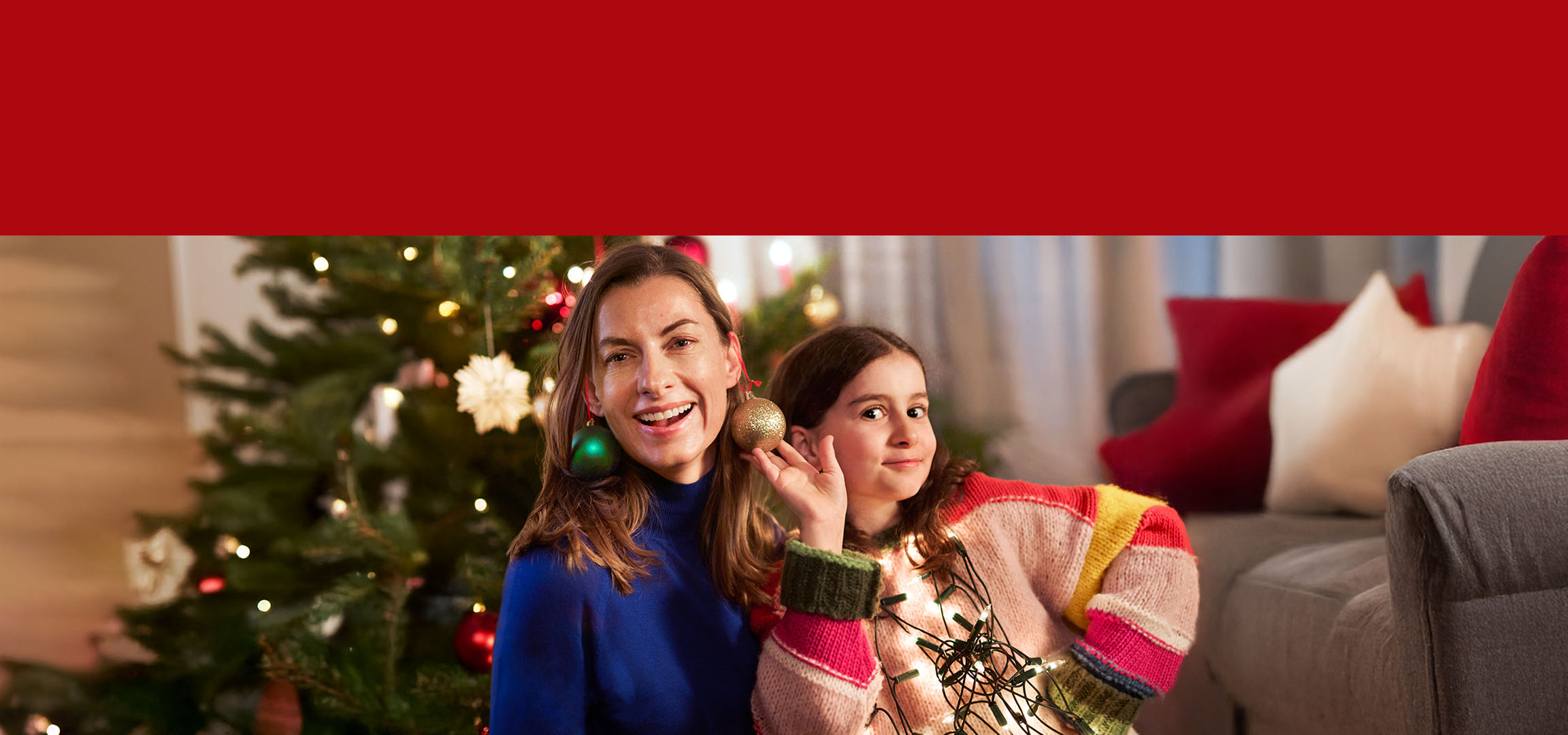 Женщина и ребенок с рождественскими украшениями, красный елочный шар