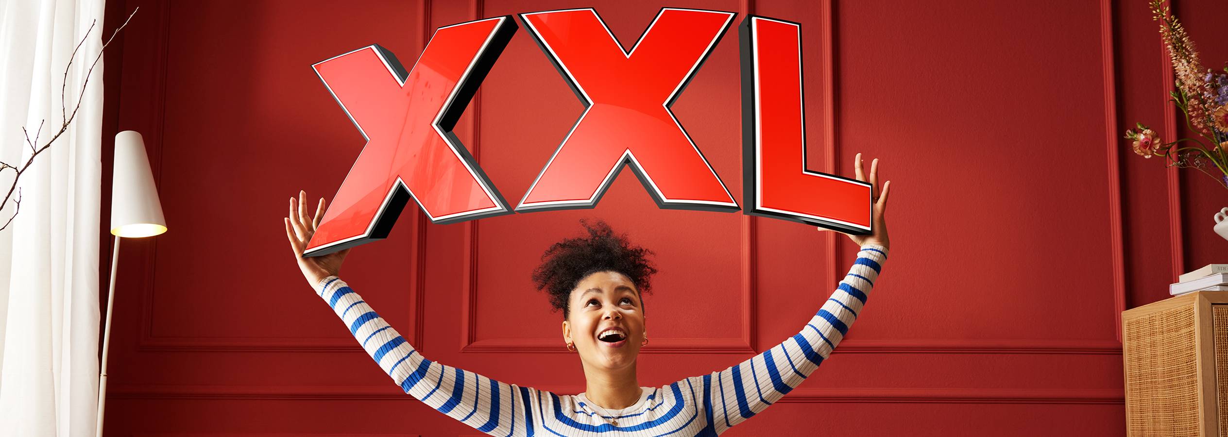 Женщина держит над головой большие красные буквы XXL.