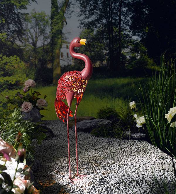 Päikesepaneeliga punane metallflamingo kaunistab aeda.