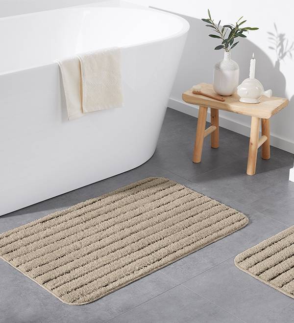 Beige värvi vannivaip ja väike jalavaip moodsas vannitoas.