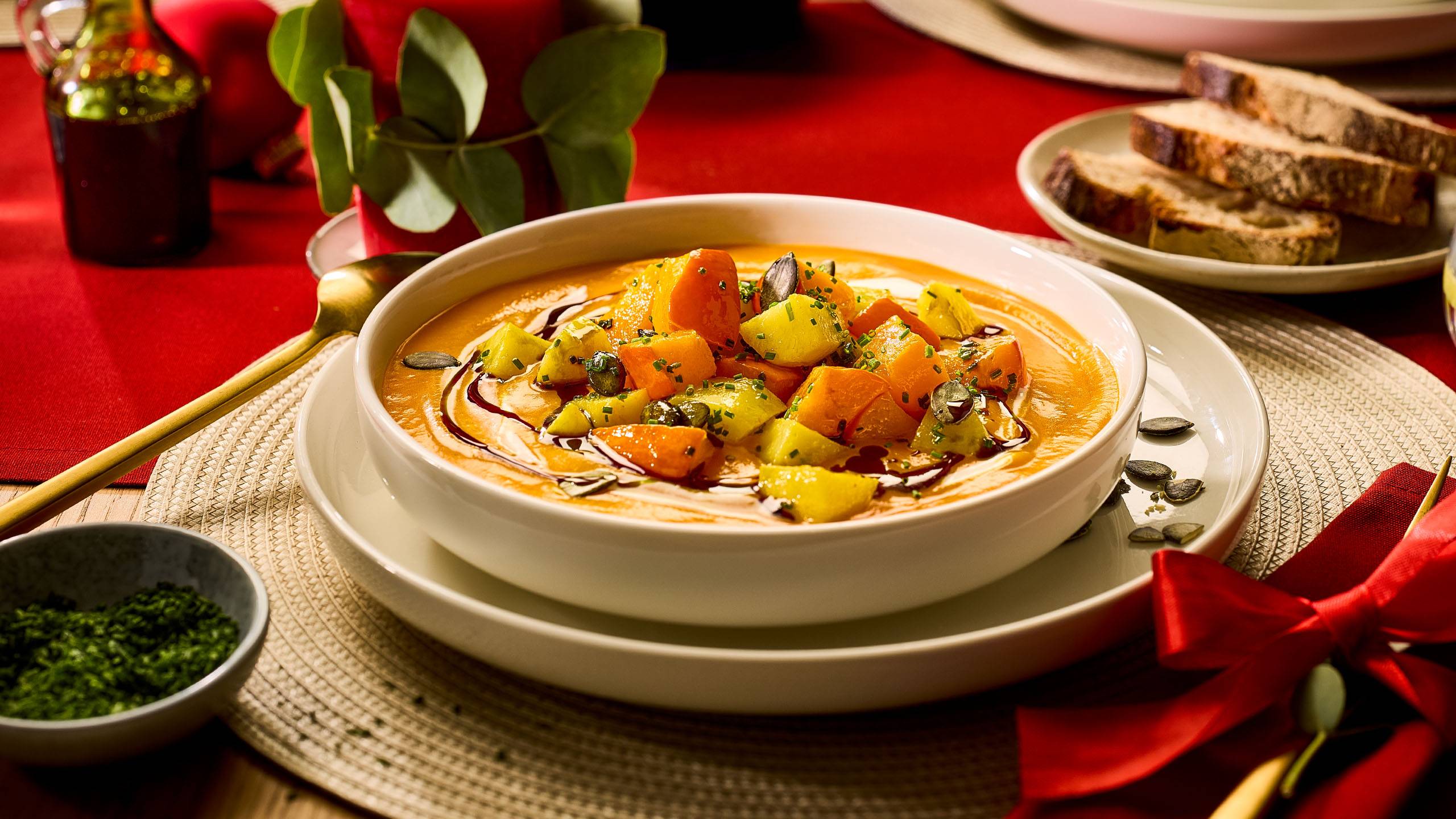 Kauss kreemja kõrvitsasupiga, kaunistatud köögiviljade, seemnete ja ürtidega, pidulikul laual.